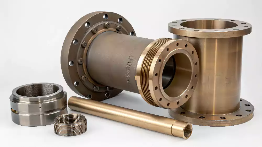 A collage of industrial parts made by centrifugal casting: a large pipe, a bronze bushing, and a cylinder liner